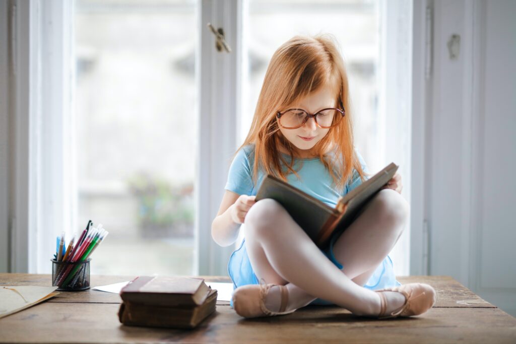 A girl sitting on the table and reading a book