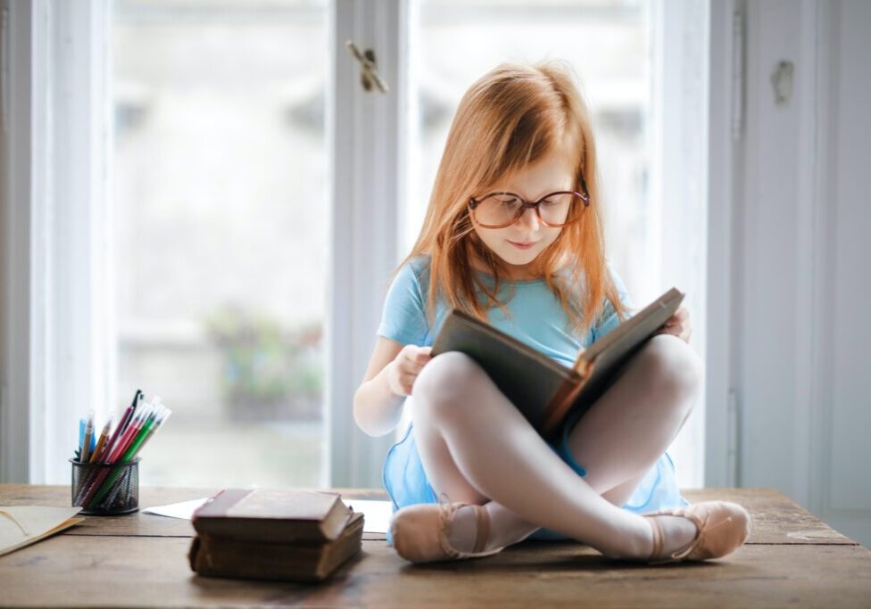 A girl sitting on the table and reading a book